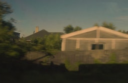 On a train at dusk, the shadow of the train is visible against the fenceline.
